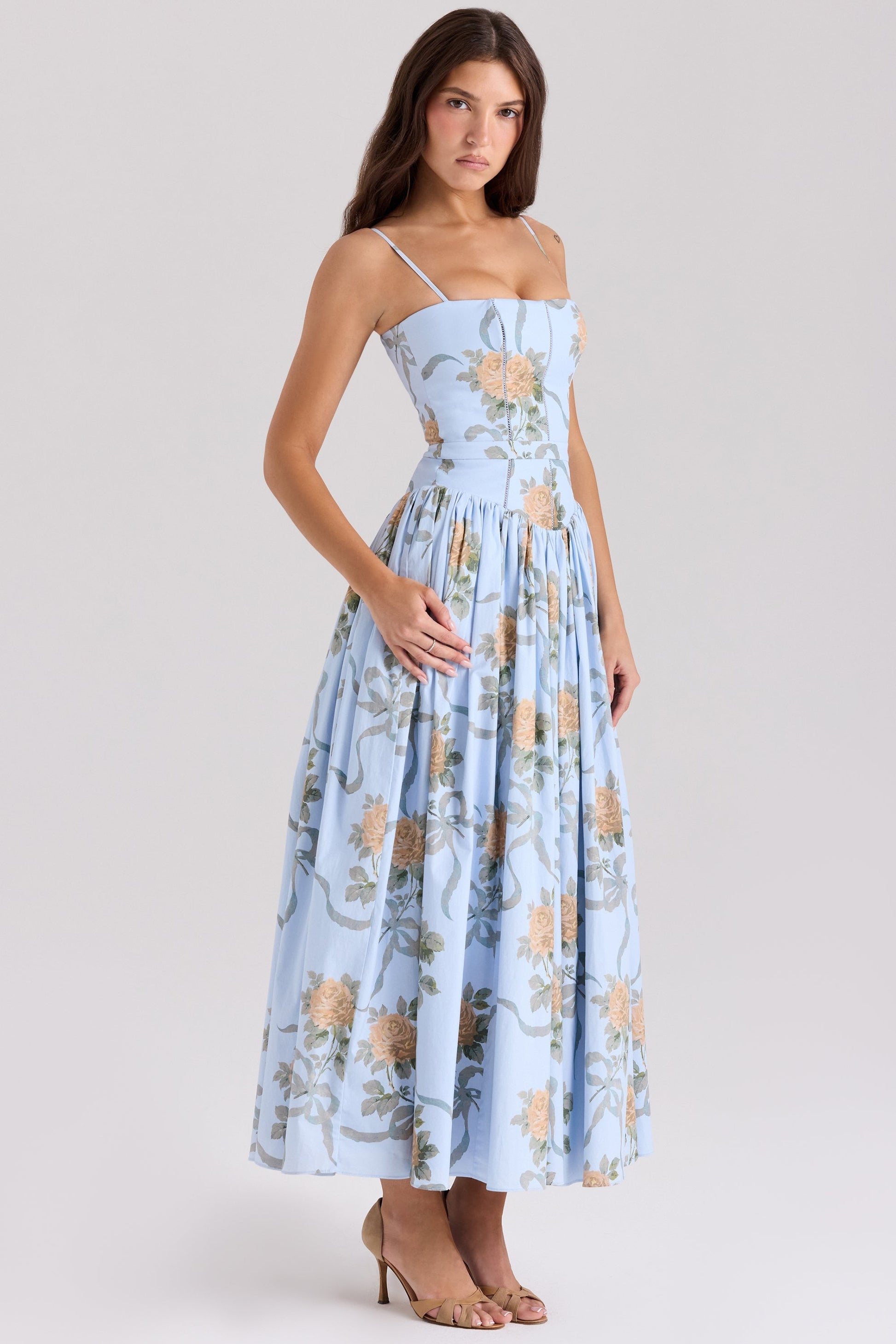 Full-length Adeline Corset Midi Dress in light blue with delicate peach rose and ribbon print, paired with nude heels.