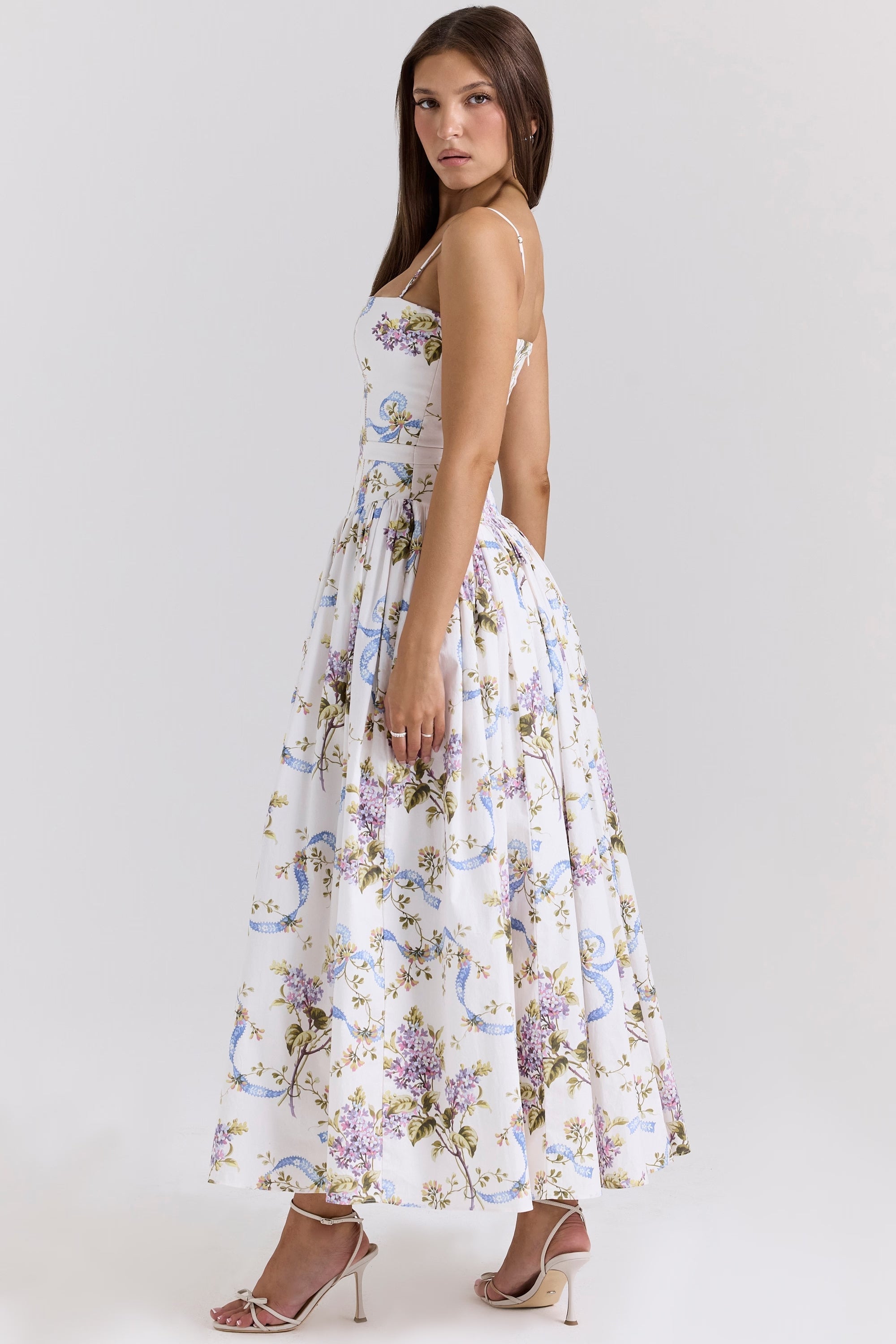 Side view of the white floral Adeline Corset Midi Dress, featuring a full gathered skirt and elegant white heels.