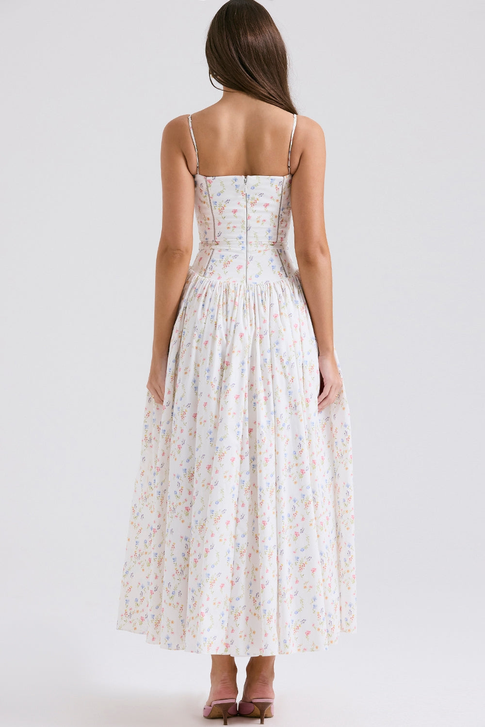 Rear view of the white Adeline Corset Midi Dress with a soft multi-color floral print, showing the back zipper and pleated skirt.