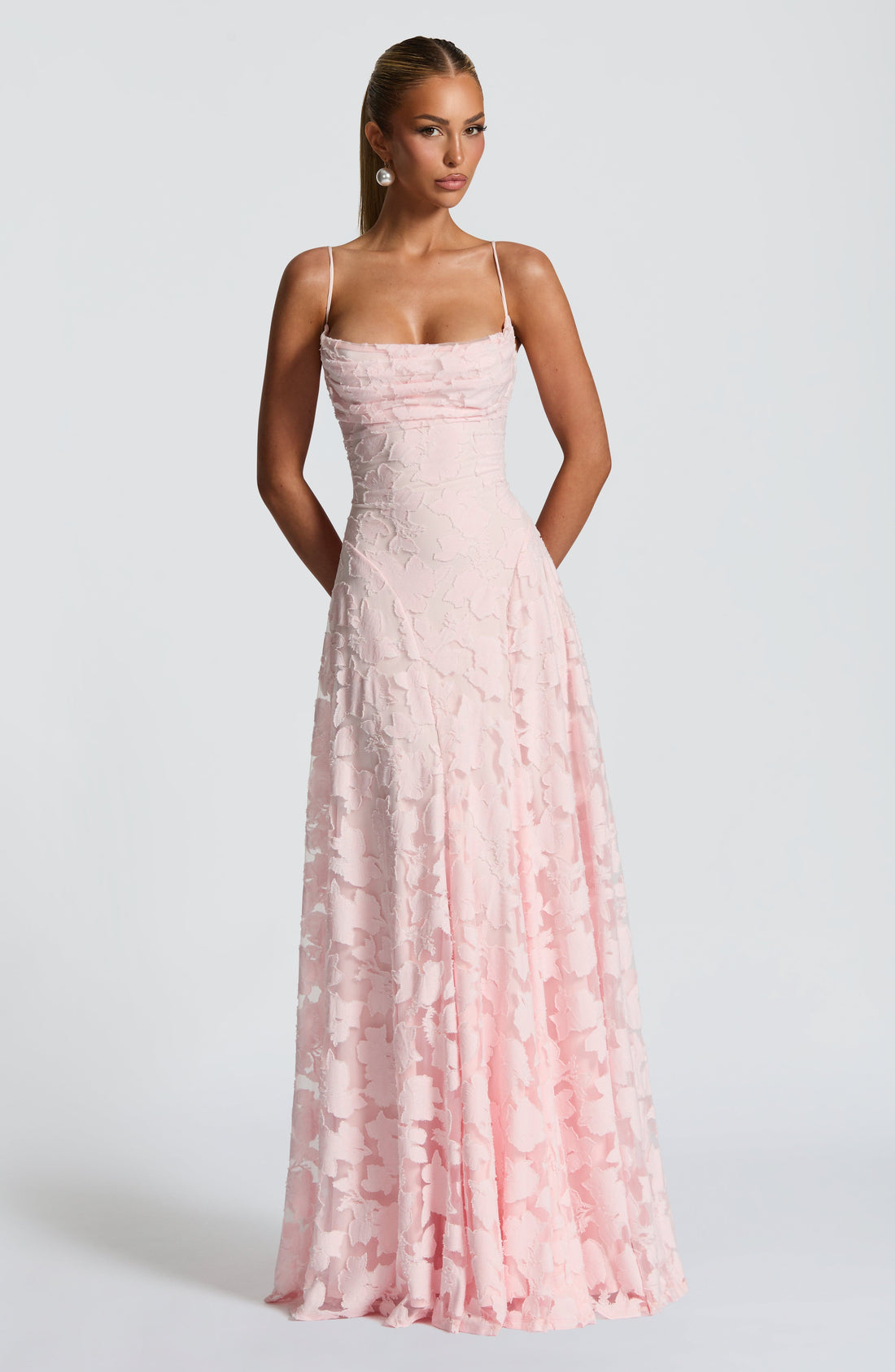 Full-length pink floral maxi dress with spaghetti straps and ruched bodice, standing by concrete steps.
