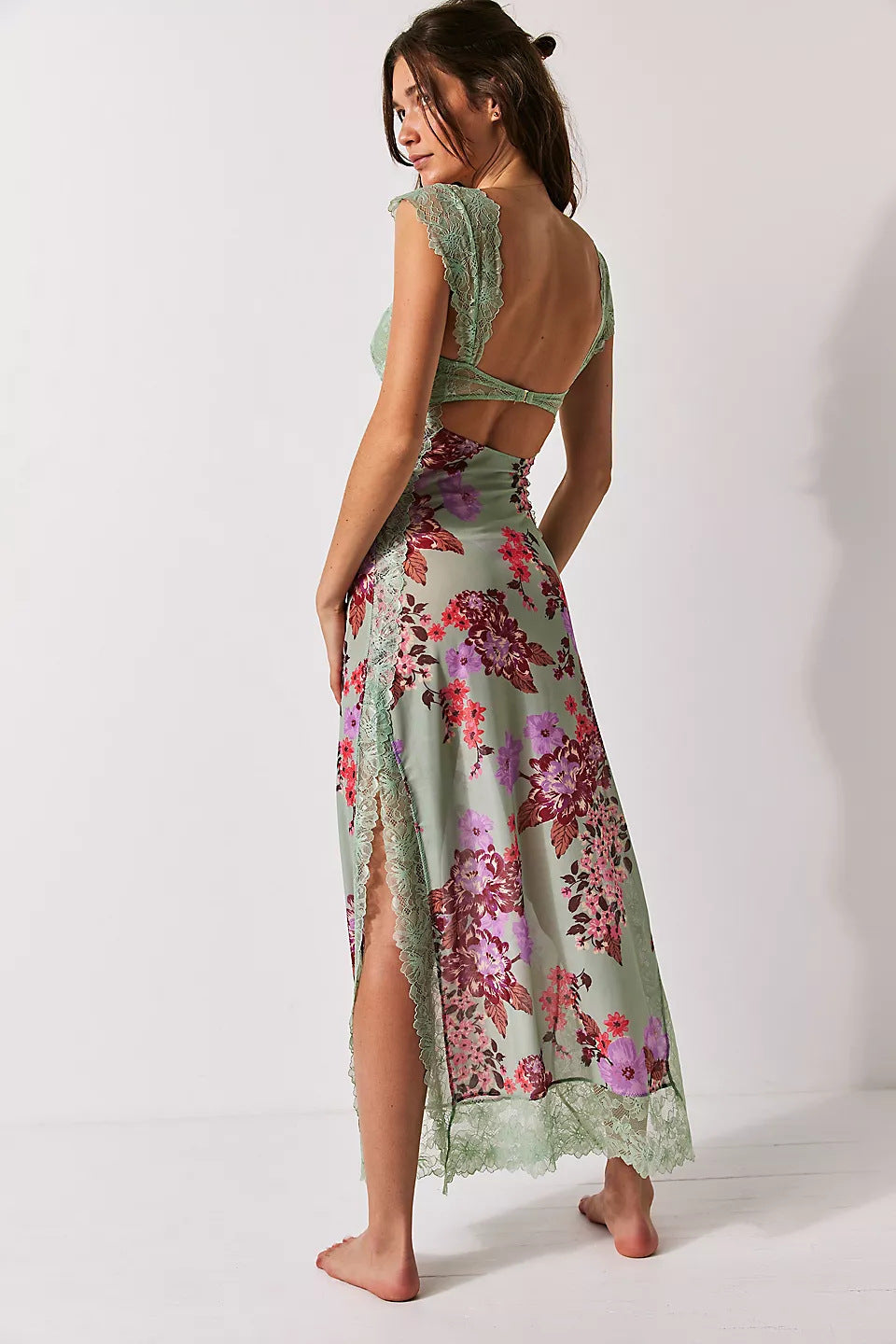 Back view of Aisha backless maxi dress in light green with pink and purple floral print, lace trim, and high leg slit.