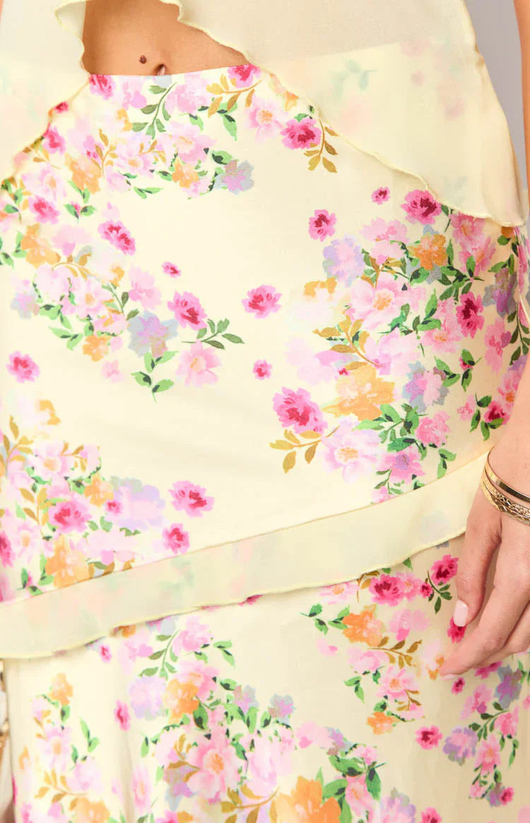 Close-up of yellow fabric with pink, orange, and purple floral print on ruffled skirt for women