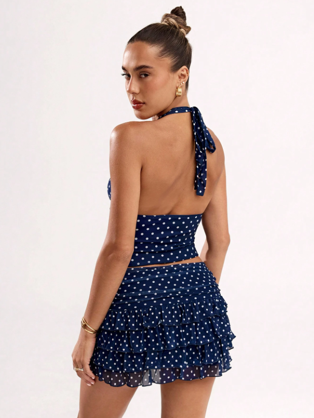 Rear view of women's navy polka dot halter crop top and ruffled mini skirt, showcasing back detail