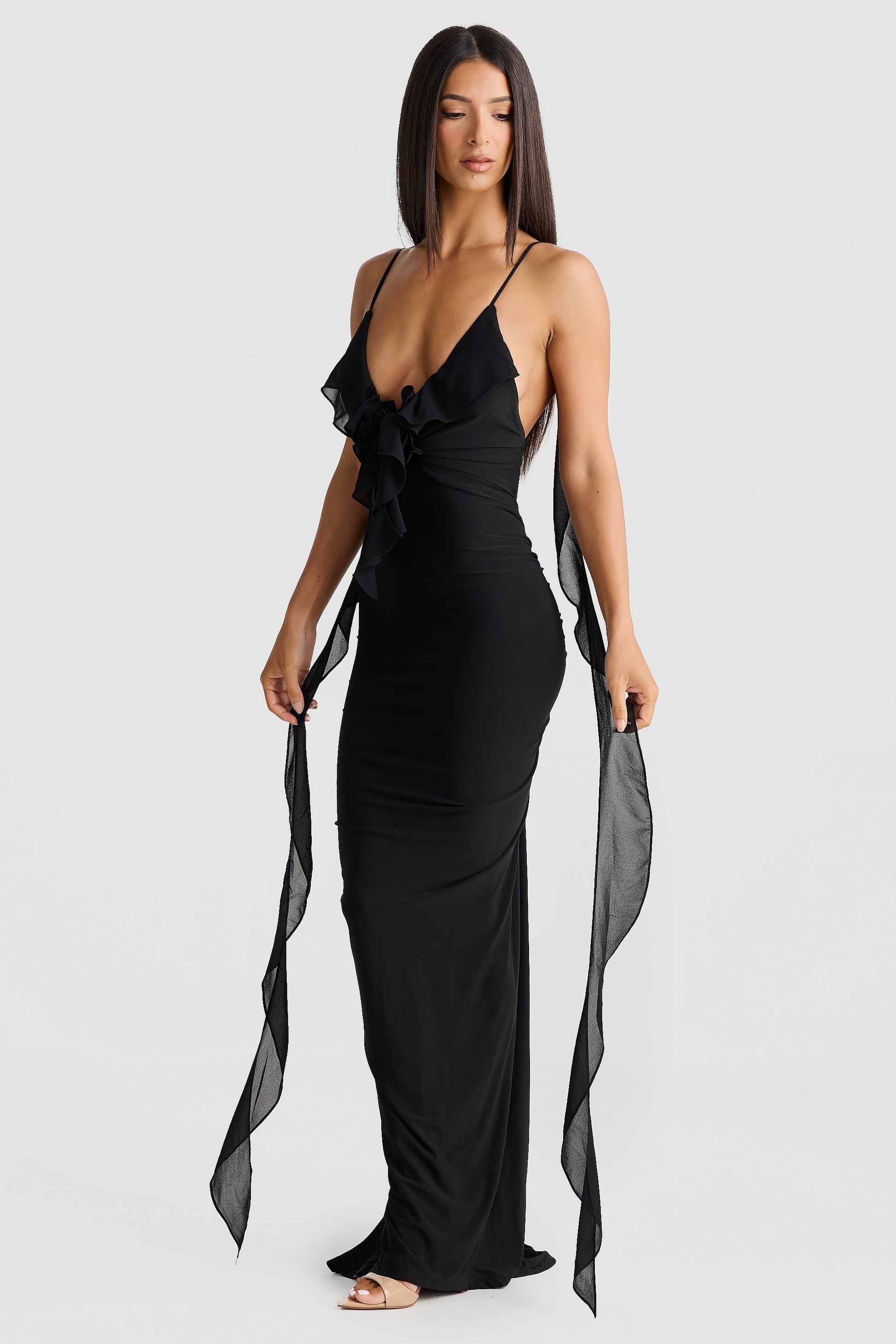 Front view of a sleek black Alexa Ruffle Maxi Dress, with a plunging V-neck, ruffled embellishment, and elegant chiffon sashes draping down.