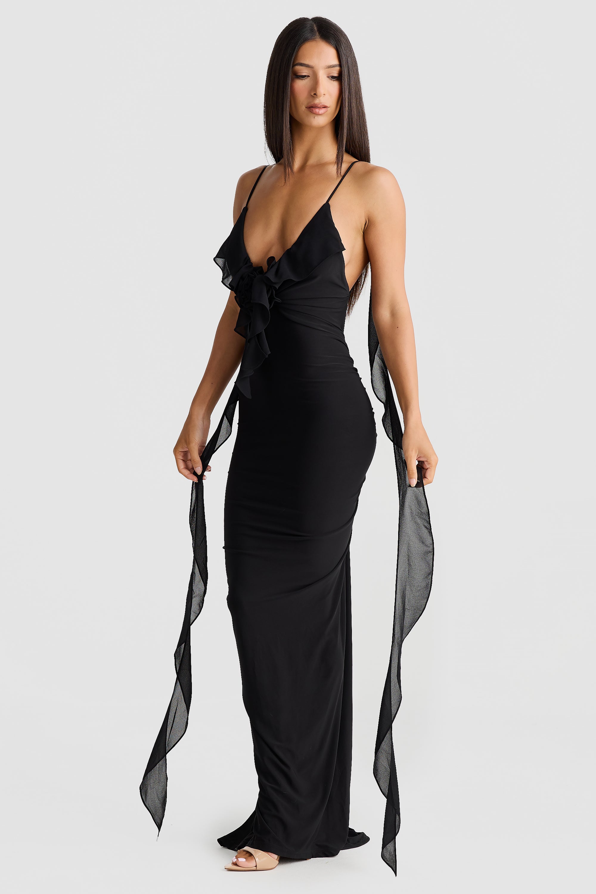 Front view of a sleek black Alexa Ruffle Maxi Dress, with a plunging V-neck, ruffled embellishment, and elegant chiffon sashes draping down.