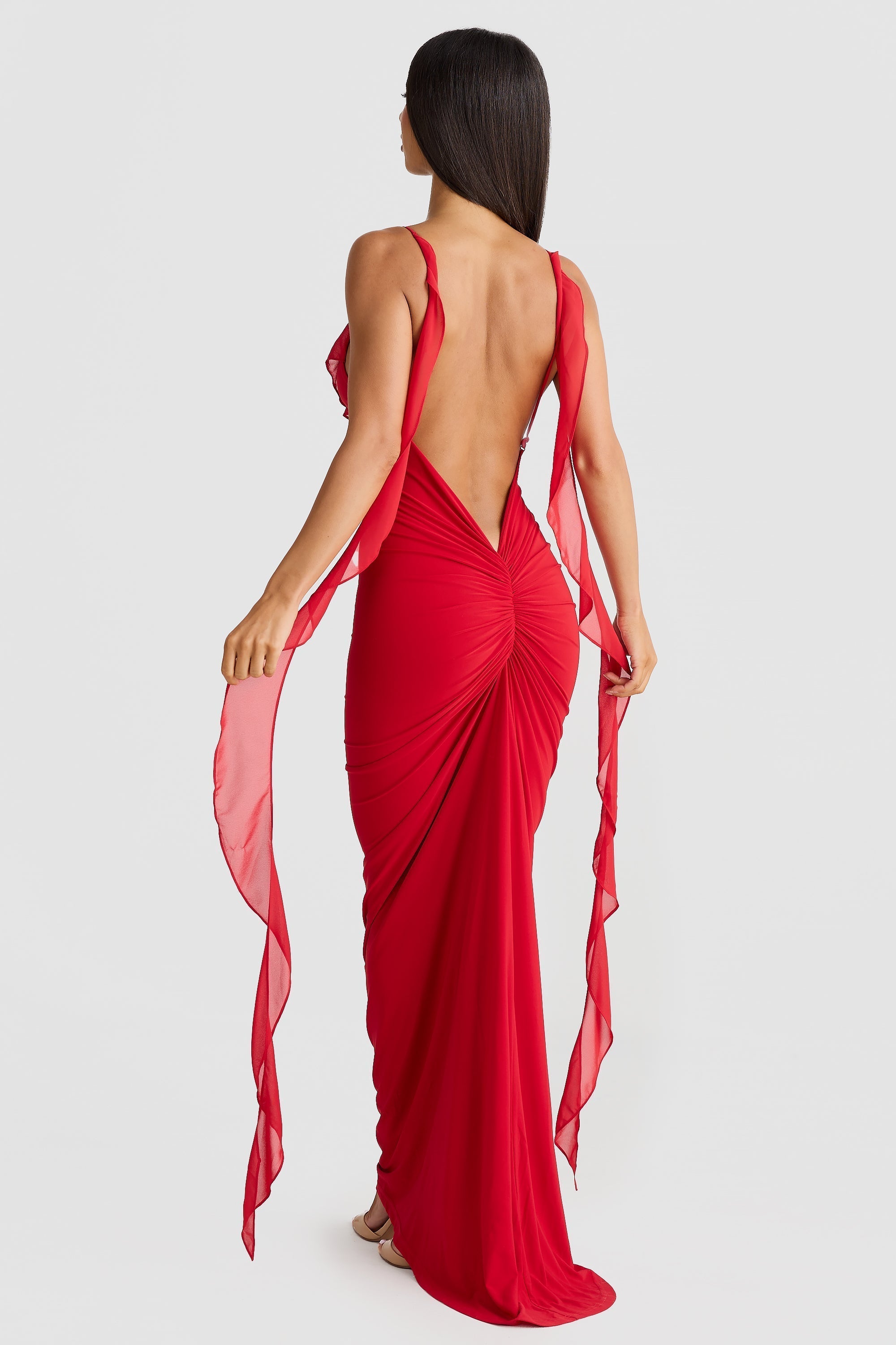 Back view of the red Alexa Ruffle Maxi Dress, showcasing the low open back, ruched skirt detail, and flowing chiffon straps.