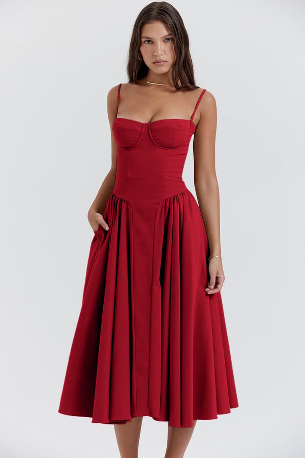 Front view of a red corset midi dress with spaghetti straps and a full pleated skirt, featuring pockets.
