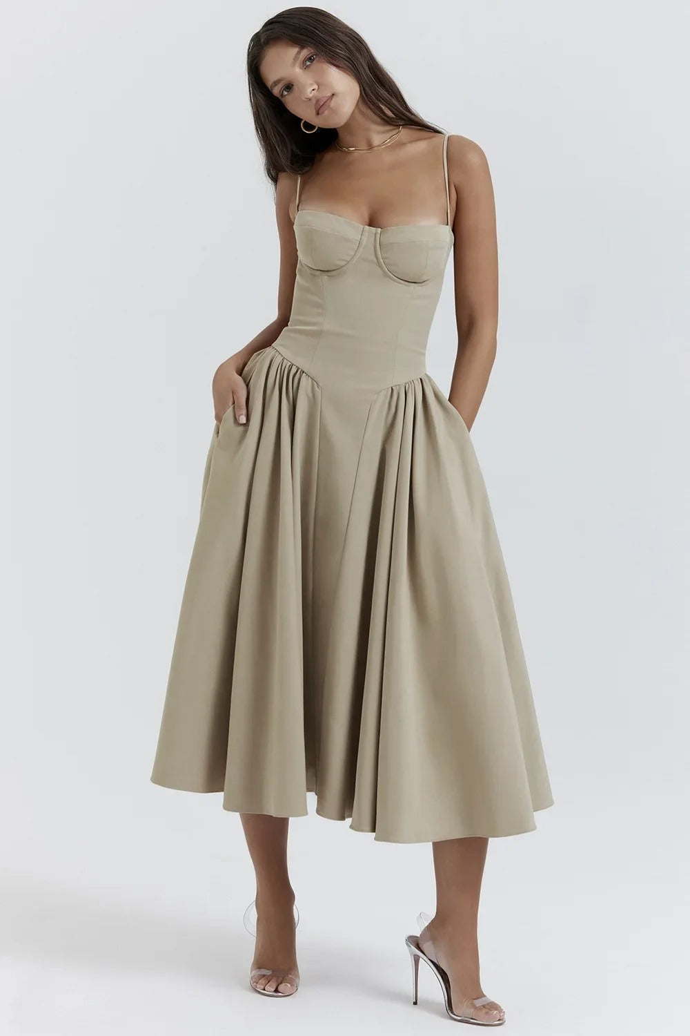 Full-length view of a light beige corset midi dress with a pleated skirt and visible pockets, paired with heels.