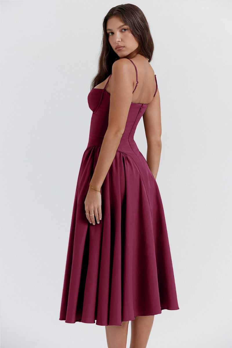 Back three-quarter view of a deep burgundy corset midi dress, showcasing the fitted bodice and flowing skirt.