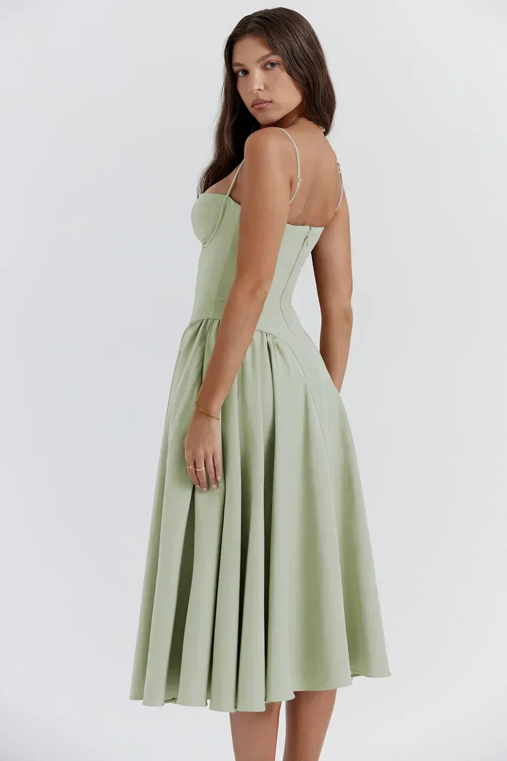 Back view of the light green Alexandra corset midi dress, showcasing the pleated skirt and thin spaghetti straps.