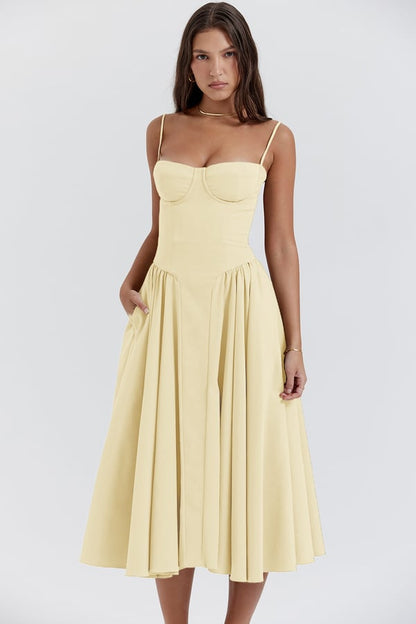 Pale yellow Alexandra corset midi dress with a sweetheart bust, thin straps, and a voluminous pleated skirt with pockets.