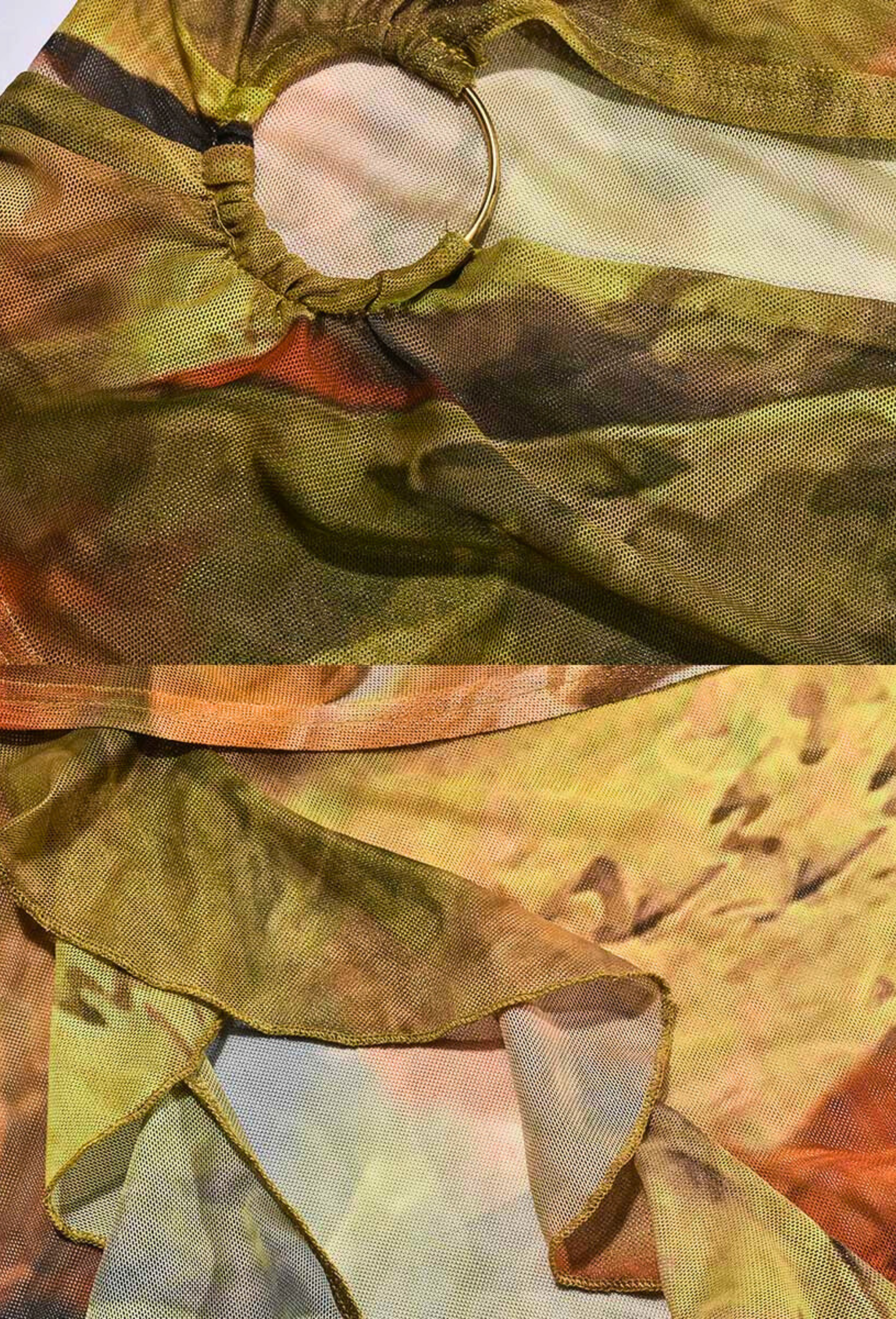 Detailed close-up of the sheer mesh fabric of the Alexandra Cutout Mini Dress, showing the gold ring accent and ruffled hem.