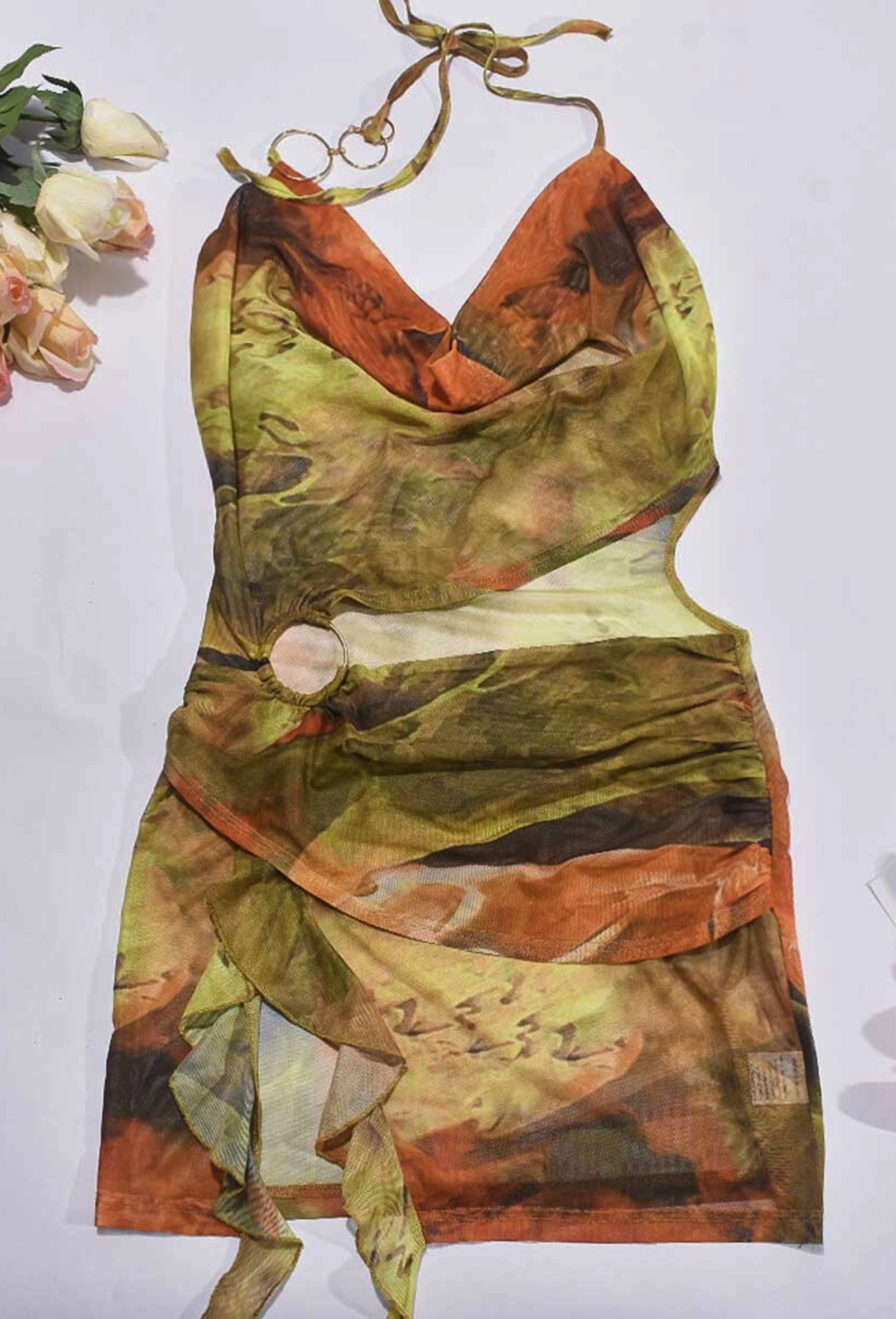 Flat lay of the Alexandra Cutout Mini Dress in green and orange abstract print, highlighting the halter neck and midriff cutout.
