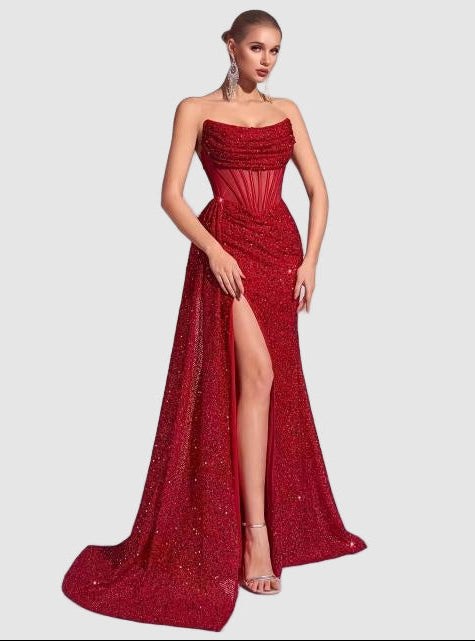 Red sequin maxi dress with a strapless design, ruched details on the bodice, and a high front slit, creating a stunning look.