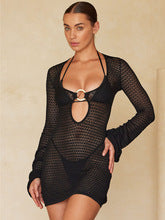 Model wearing a black crochet mini dress over a black bikini, featuring long sleeves and a front O-ring cutout.