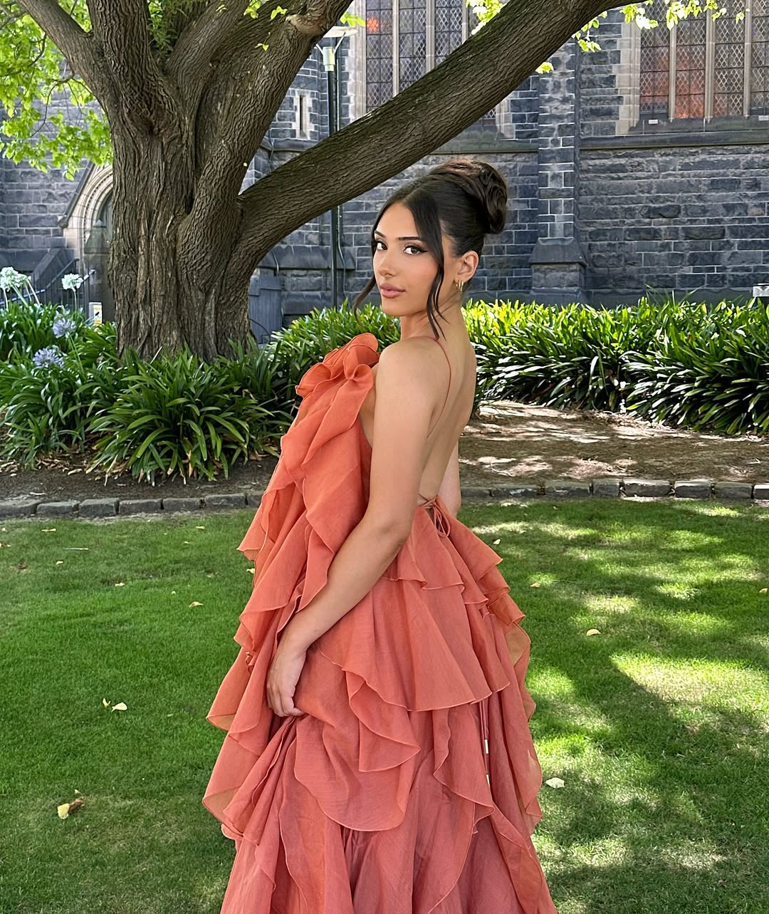 Back view of the peach Andrea Ruffle Maxi Dress, showcasing the open back and cascading ruffles.