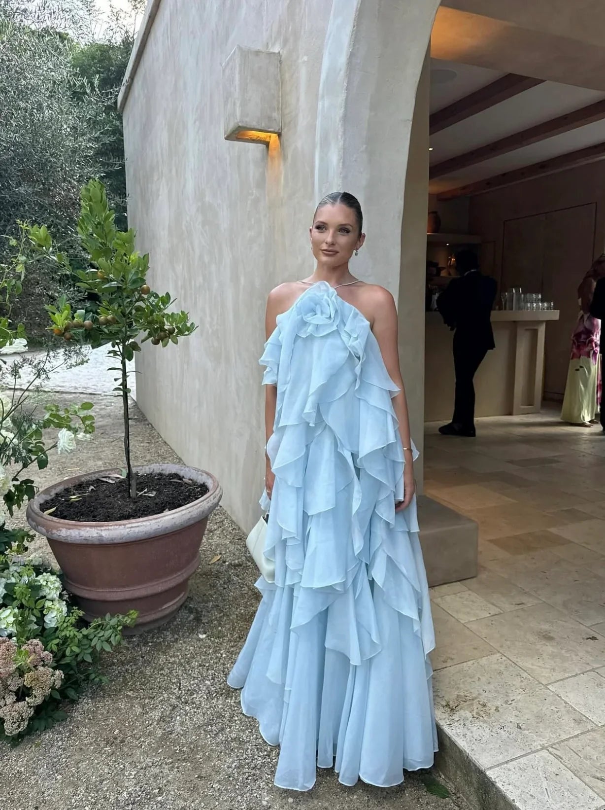 Elegant light blue Andrea Ruffle Maxi Dress with layered ruffles, worn outdoors at an event.