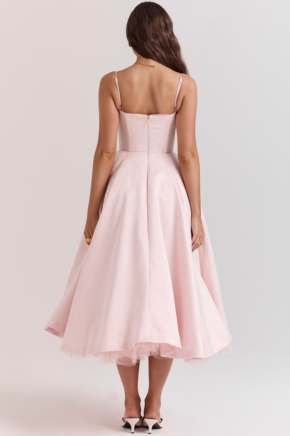Back view of a light pink corset midi dress, showing the fitted bodice, full skirt, and white designer shoes.