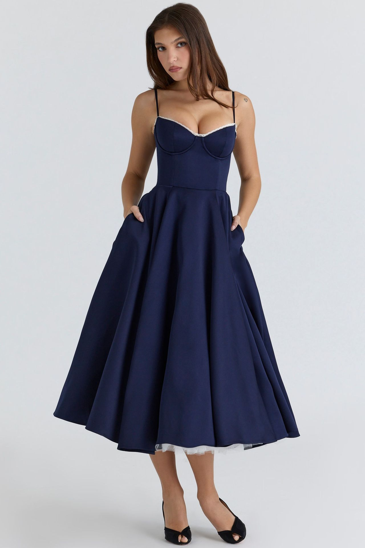 Front view of a navy blue Angela Corset Midi Dress with a full skirt and practical pockets, showing white lace trim on the bust.