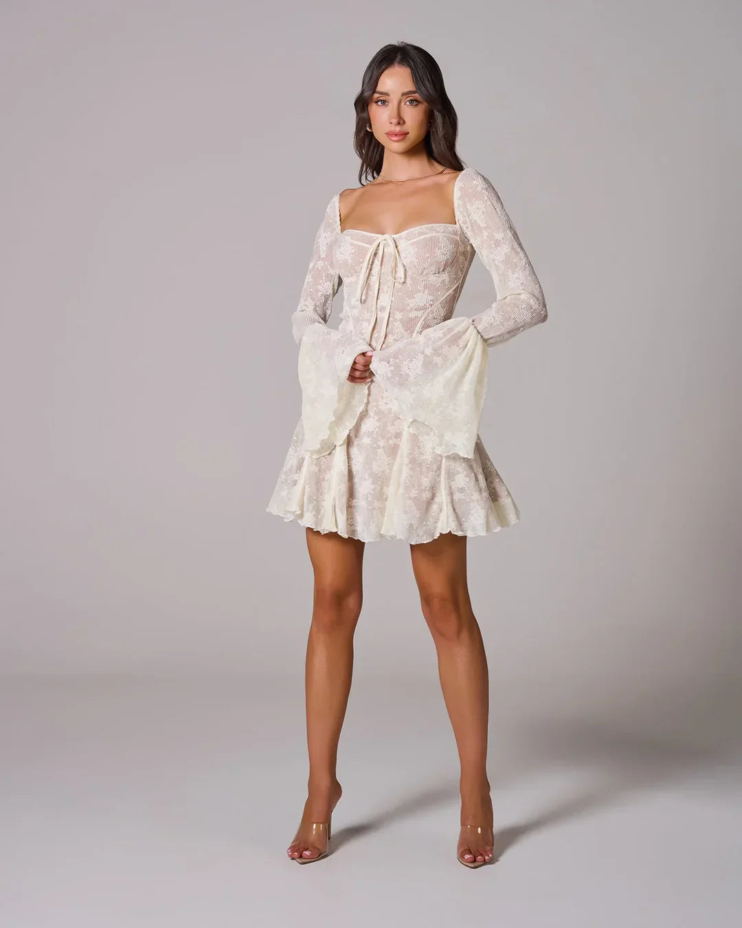 Cream white lace mini dress with a square neckline, long bell sleeves, and a fitted bustier-style bodice with a front tie.