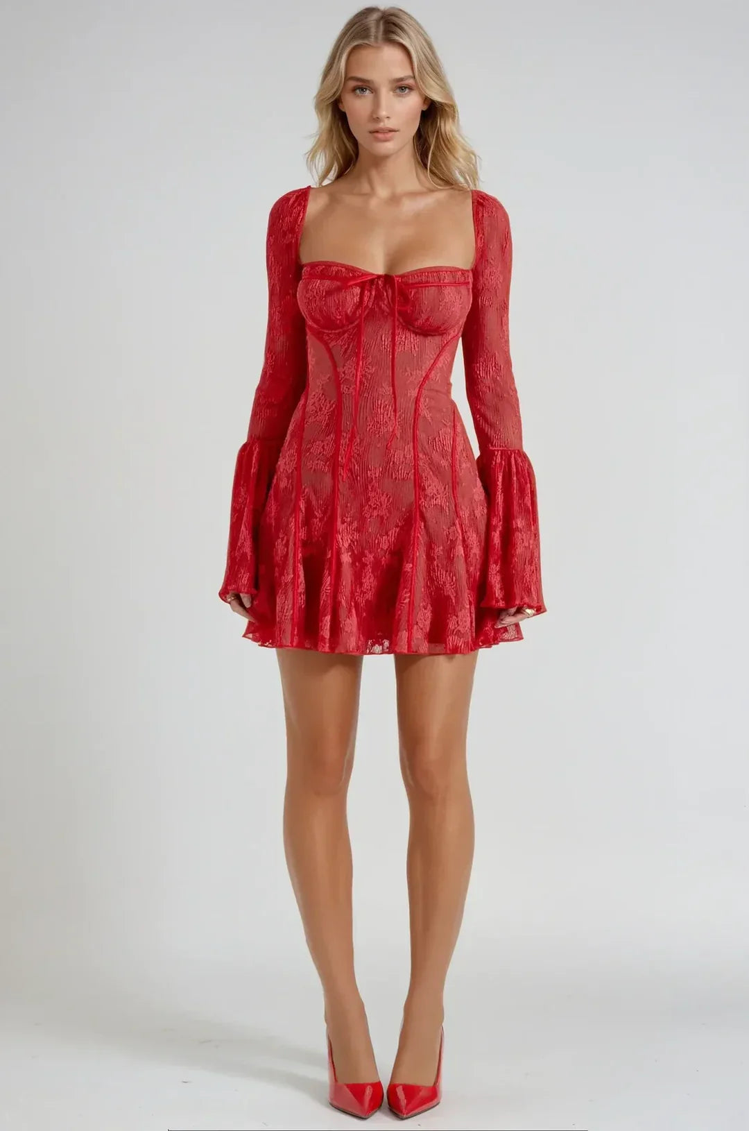 Full-length front view of a woman in a vibrant red lace mini dress with a square neckline and long bell sleeves, with matching red heels.