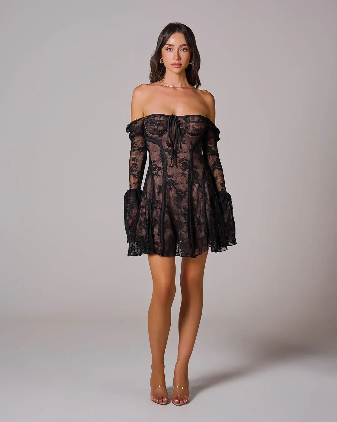 Black lace mini dress worn off-the-shoulder, featuring a square neckline, long bell sleeves, and a fitted bodice with a tie detail.