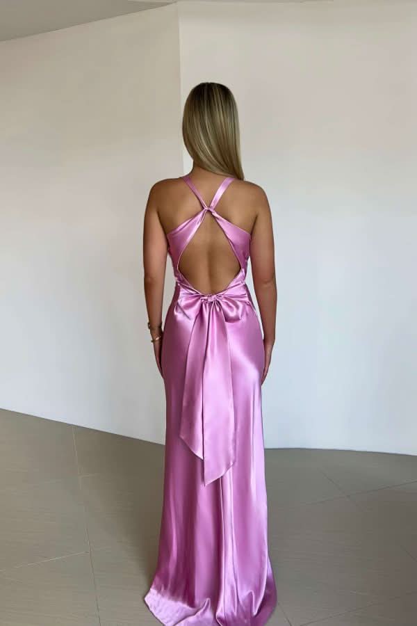 Back view of a vibrant pink satin maxi dress, showcasing the criss-cross straps and elegant bow tie detail.