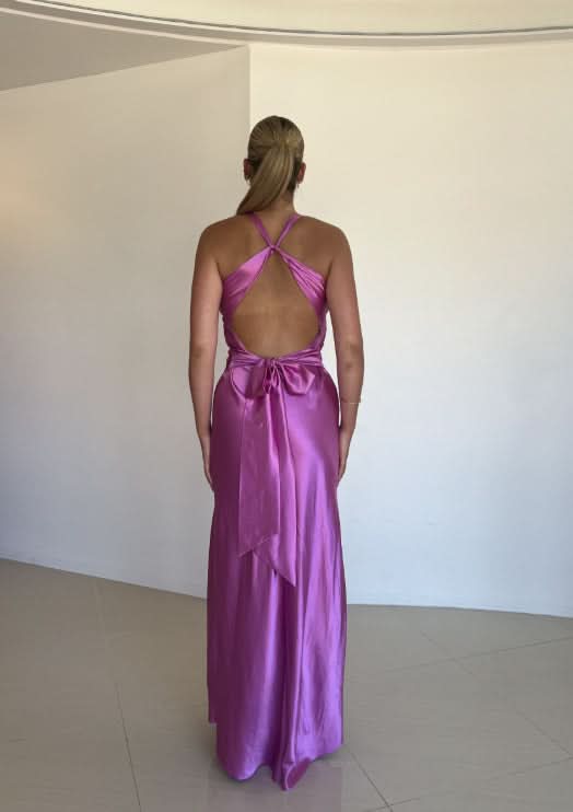 Rear view of a light purple satin maxi dress, highlighting the open back design with a tied bow at the lower back.