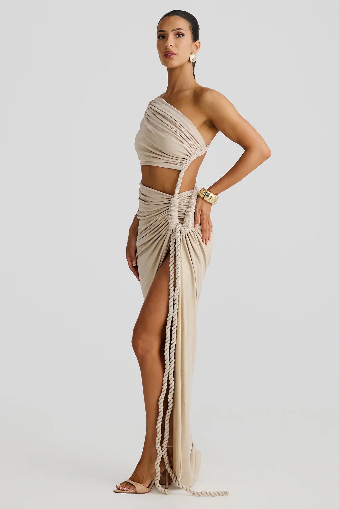Side view of the light gold Aspen Rope Maxi Dress, highlighting the one-shoulder top and the ruched skirt with prominent rope detailing.