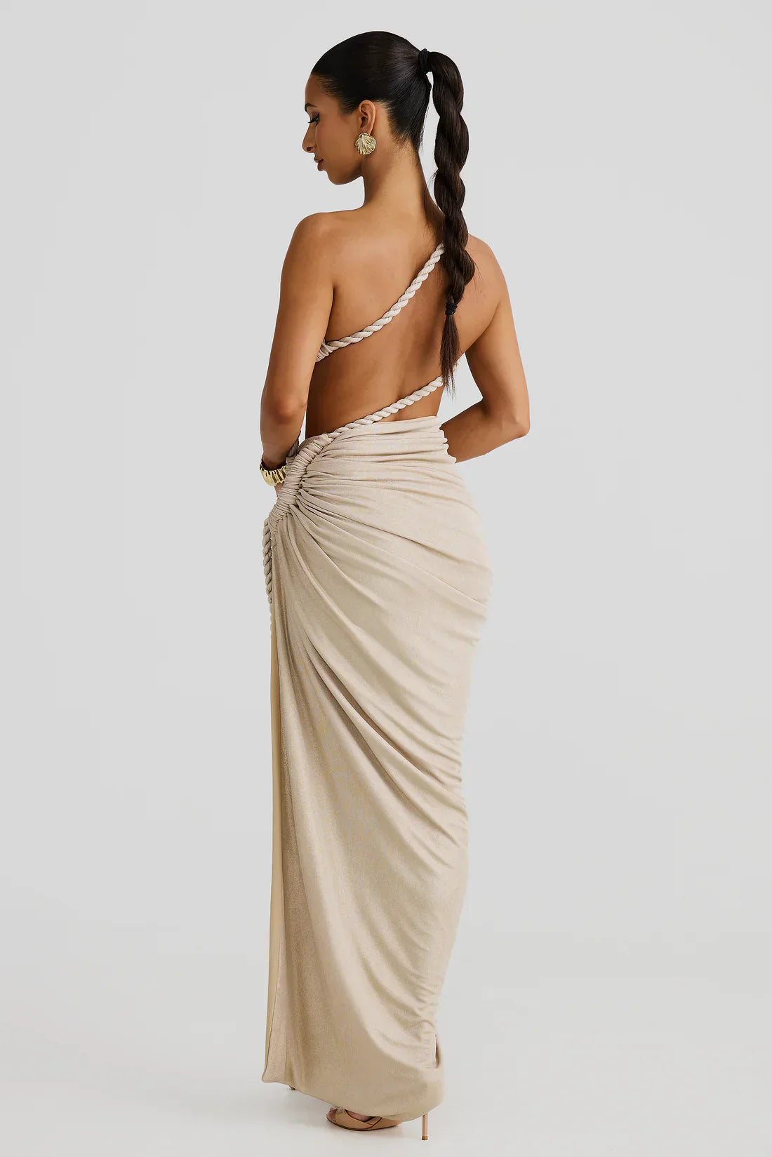 Rear view of the shimmering light gold Aspen Rope Maxi Dress, featuring the open back with a braided rope strap and draped skirt.