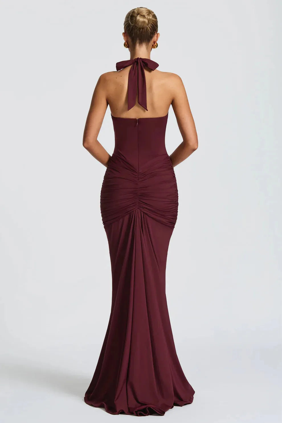 Back view of a burgundy ruched maxi dress, showing the halter tie and gathered fabric on the lower back.
