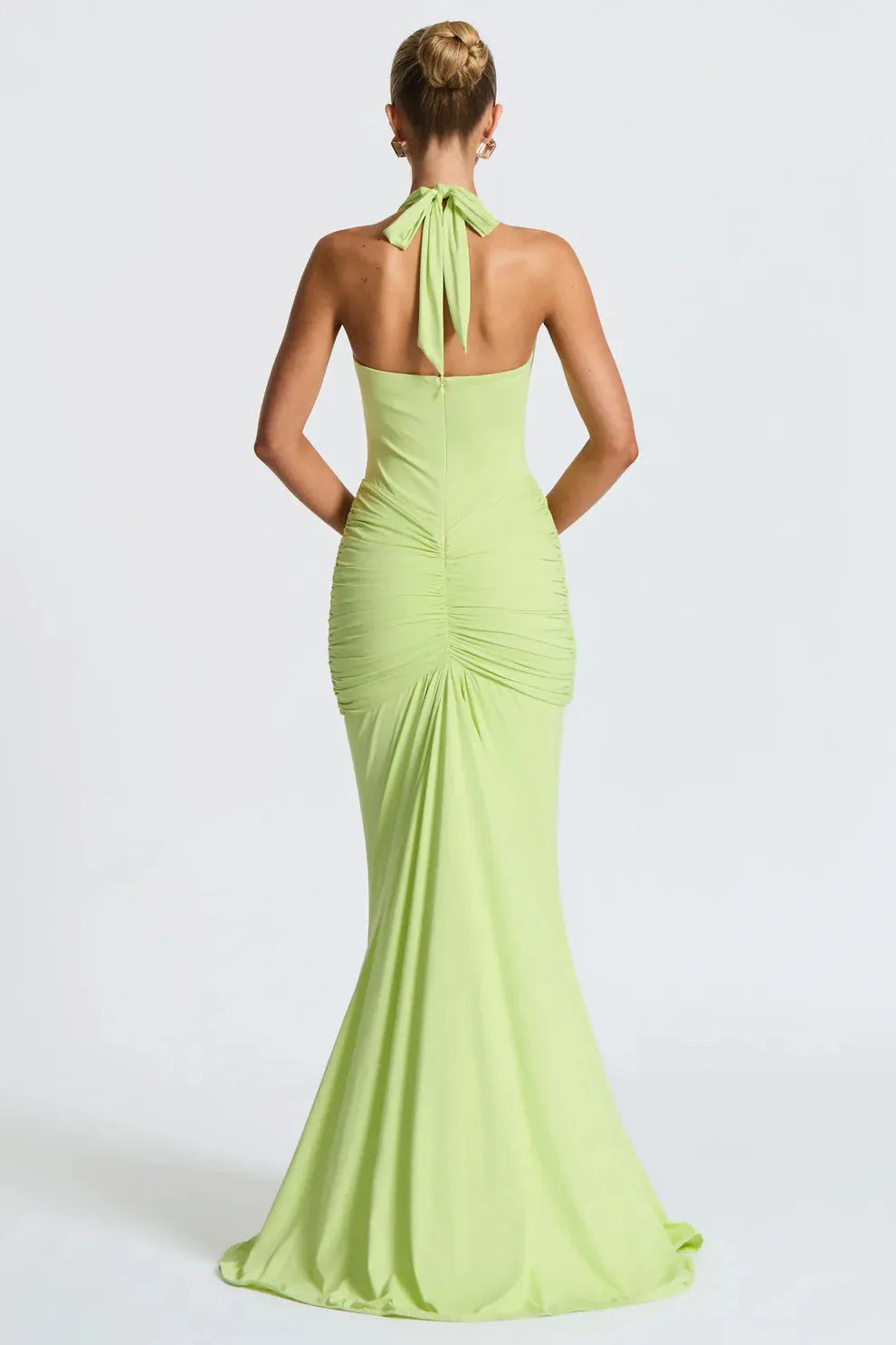 Back view of a lime green Serena ruched maxi dress, featuring a tied halter neck and gathered ruching on the back.