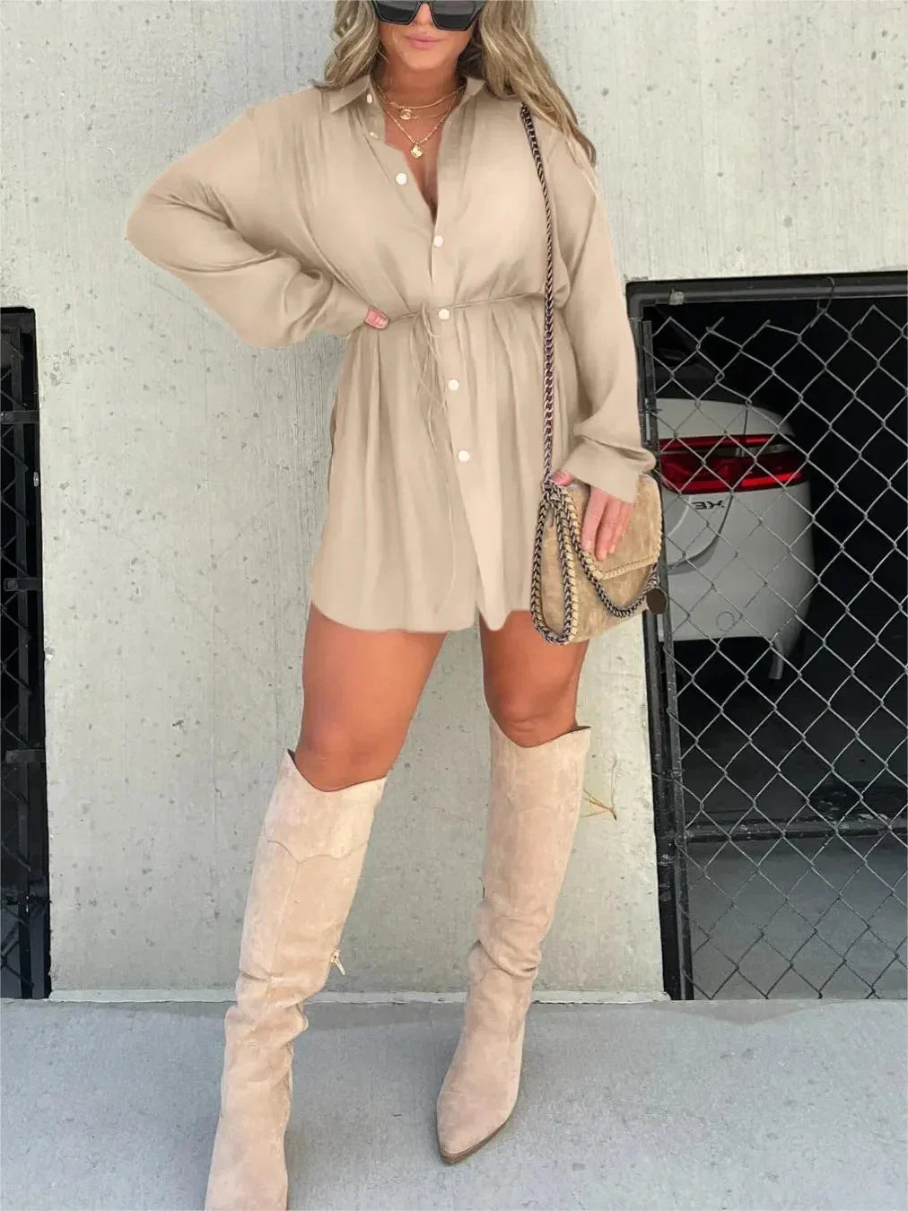 Beige Belle Button Mini Romper with white buttons and a drawstring waist, paired with knee-high suede boots and a crossbody bag.