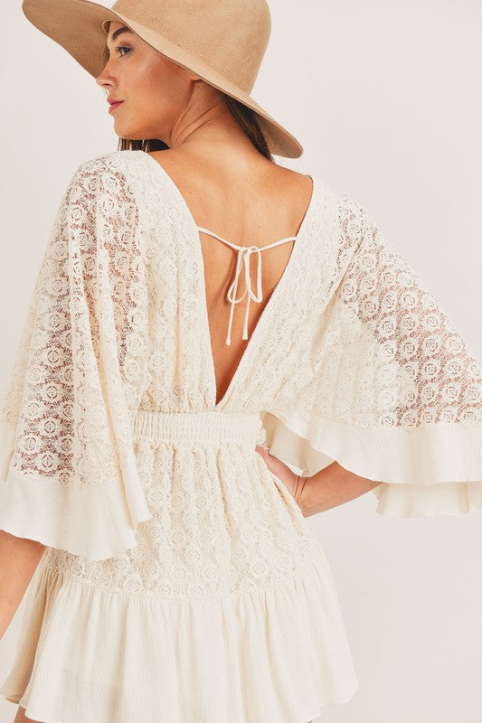 Detailed back view of the Cali lace mini dress, focusing on the lace pattern, smocked waist, and the V-back design with tie.