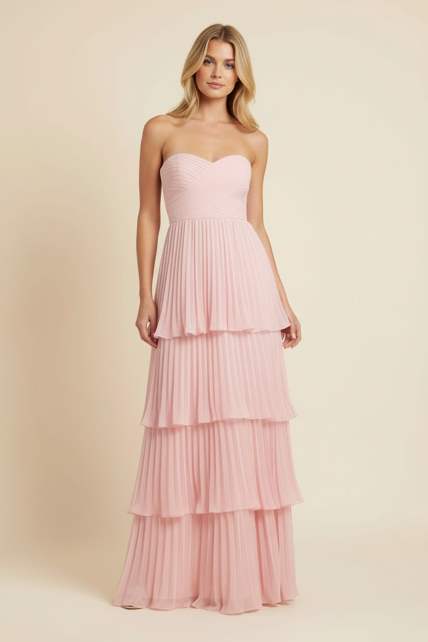 Studio shot of a woman in a full-length, strapless pink tiered maxi dress with a pleated skirt design
