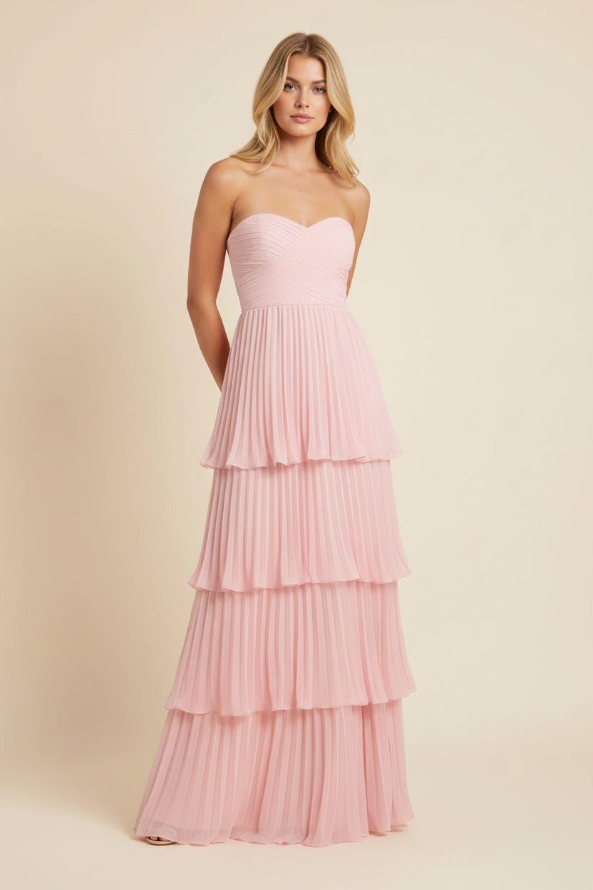 Front studio view of a blonde woman wearing a light pink tiered maxi dress, showcasing the pleated layers