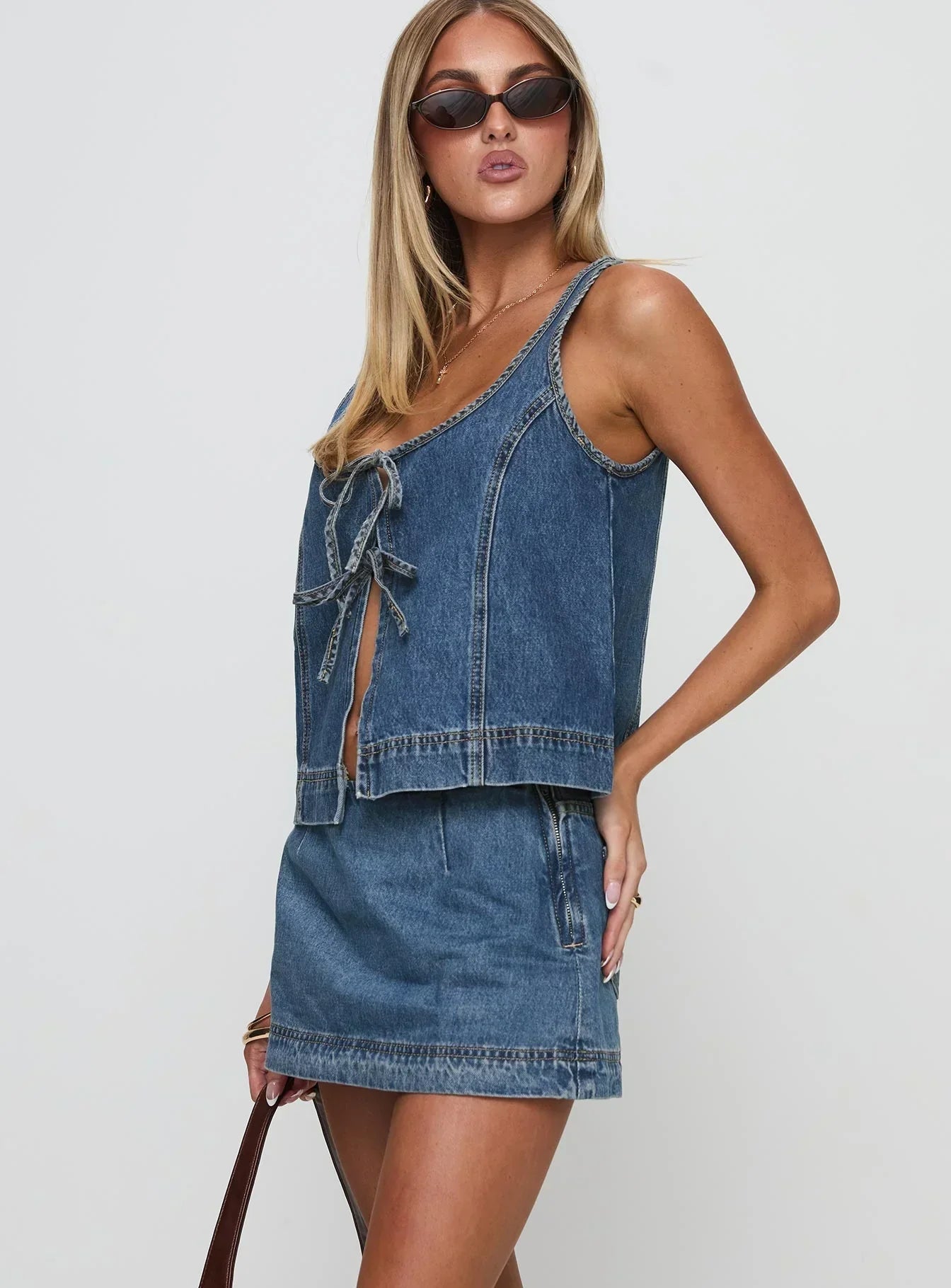 Side profile of a woman showcasing the tie-front detail of the blue denim crop top and mini skirt for women