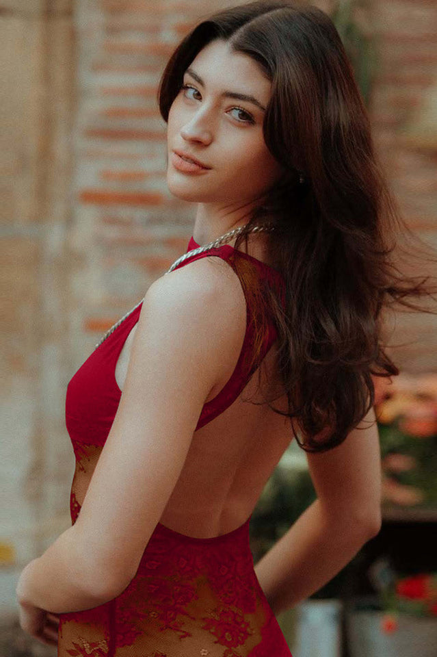 Close-up of a woman wearing a red lace maxi dress, showcasing the intricate lace pattern on the side panel.