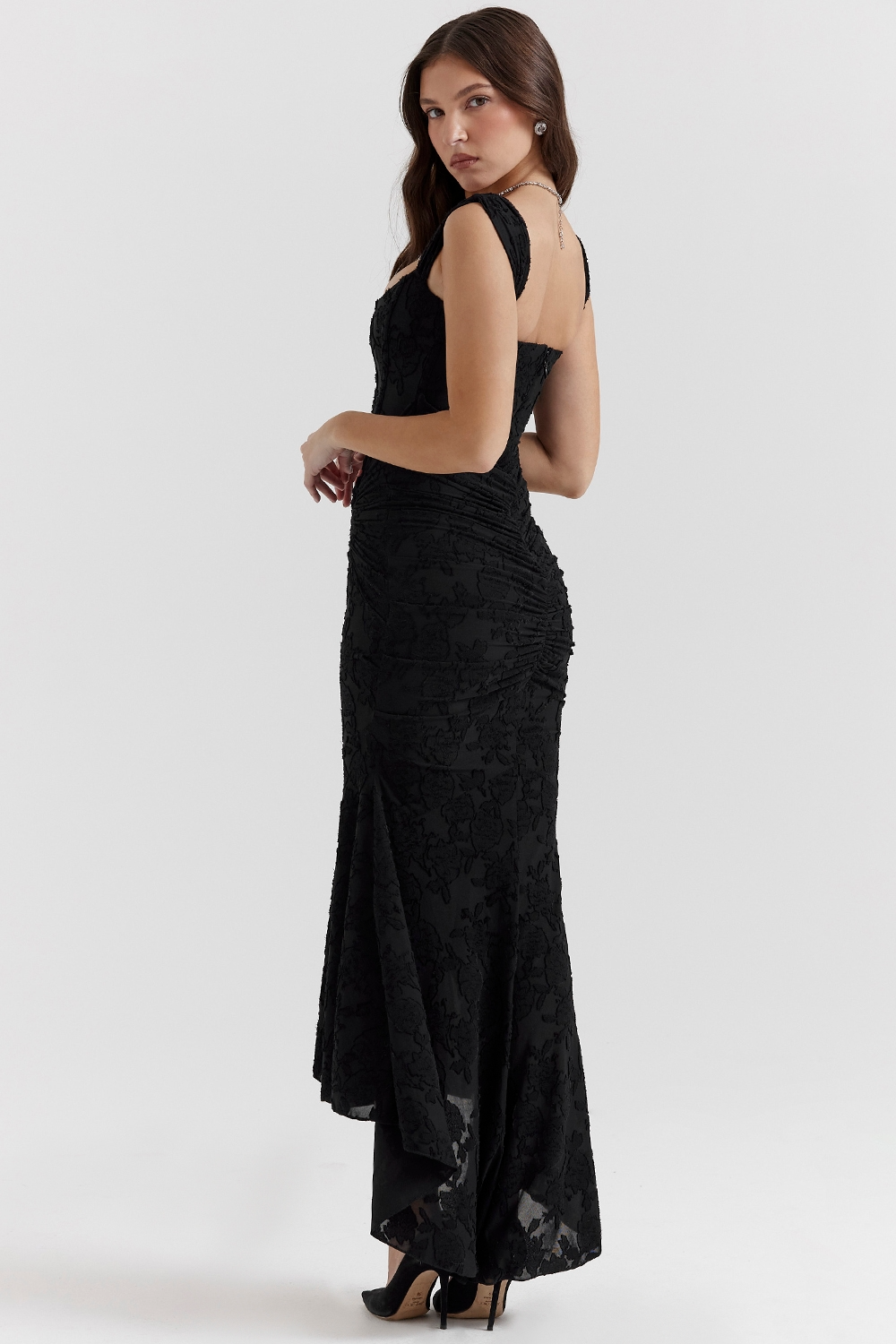 Three-quarter side view of the black Carie corset maxi dress, highlighting the fitted bodice and flowing skirt.