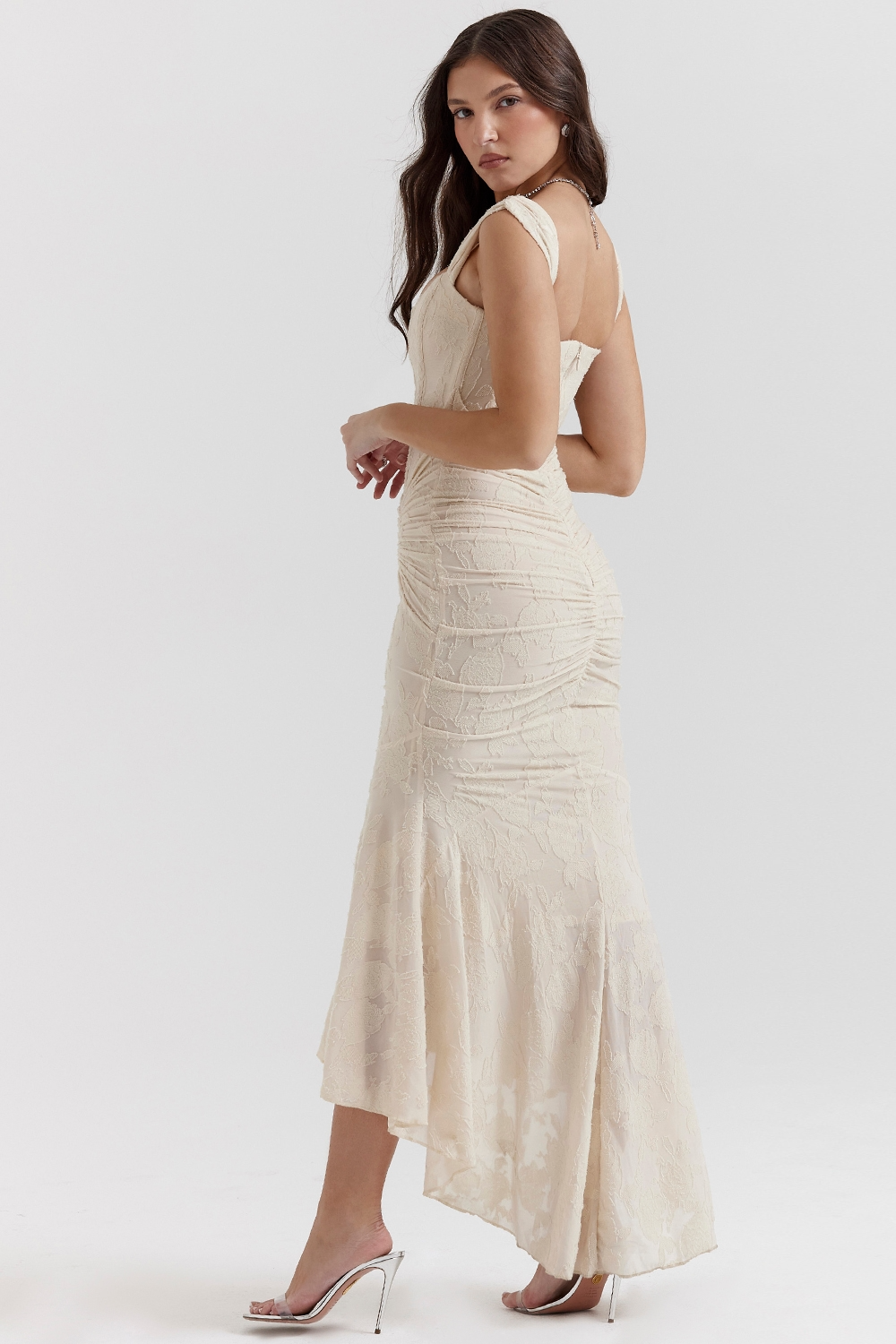Back view of a champagne floral jacquard corset maxi dress with ruched details and a high-low hem, showcasing the full skirt.