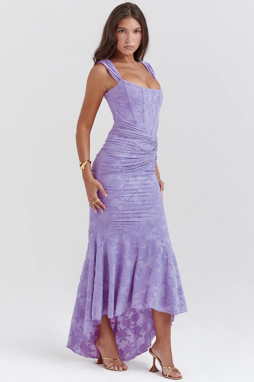 Side profile of a lilac corset maxi dress featuring a high-low hem and delicate floral jacquard pattern.