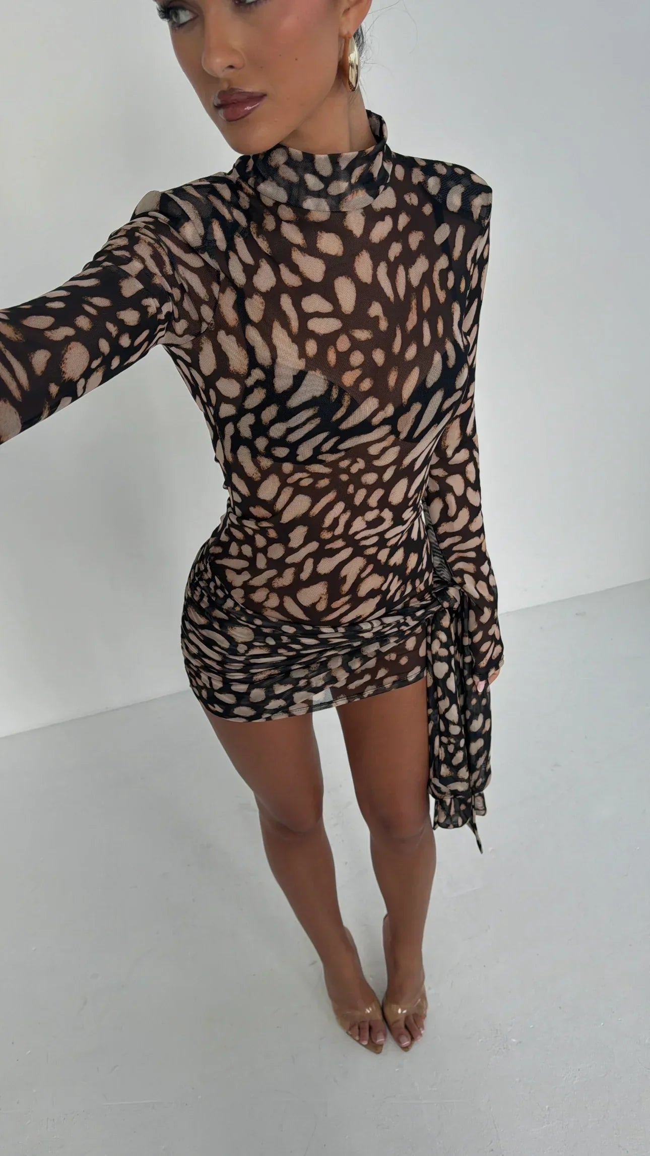 Overhead view of the Carina Ruched Mini Dress, highlighting the sheer brown and black animal print, high neckline, and bodycon fit with a draped side detail.