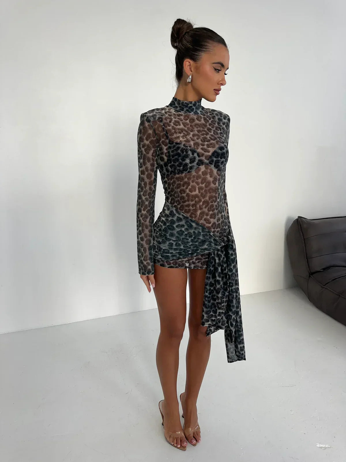 Side profile of the Carina Ruched Mini Dress, highlighting the sheer dark grey and black animal print, high neck, long sleeves, and the elegant side drape.