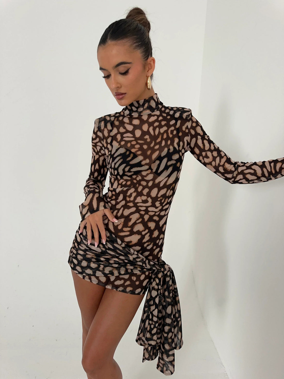 Carina Ruched Mini Dress in a sheer brown and black animal print with a high neck and long sleeves, featuring a draped ruched detail on the side.