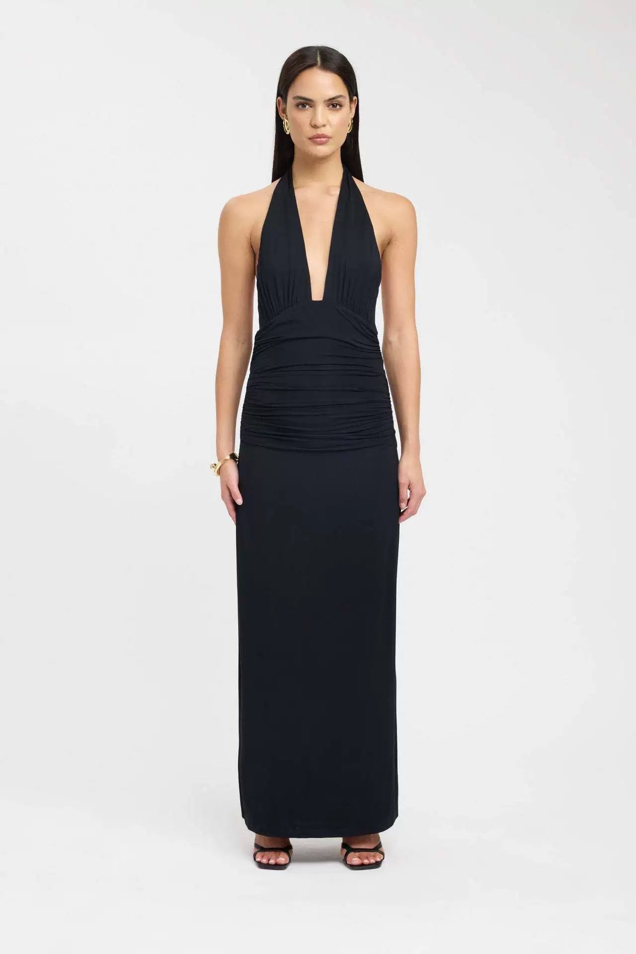 Full-length view of a black ruched maxi dress, featuring a halter neckline and gathered detailing on the bodice.