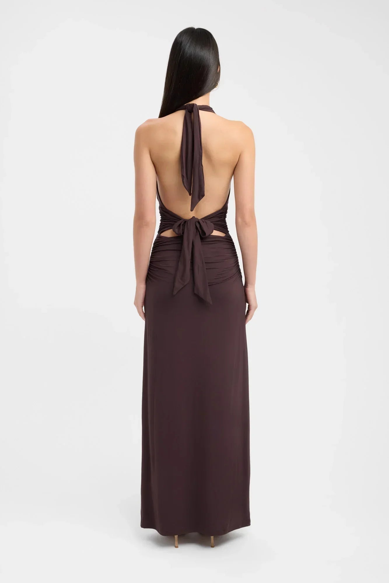 Back view of a dark brown ruched maxi dress, showing the tie-back halter neck and open back design.
