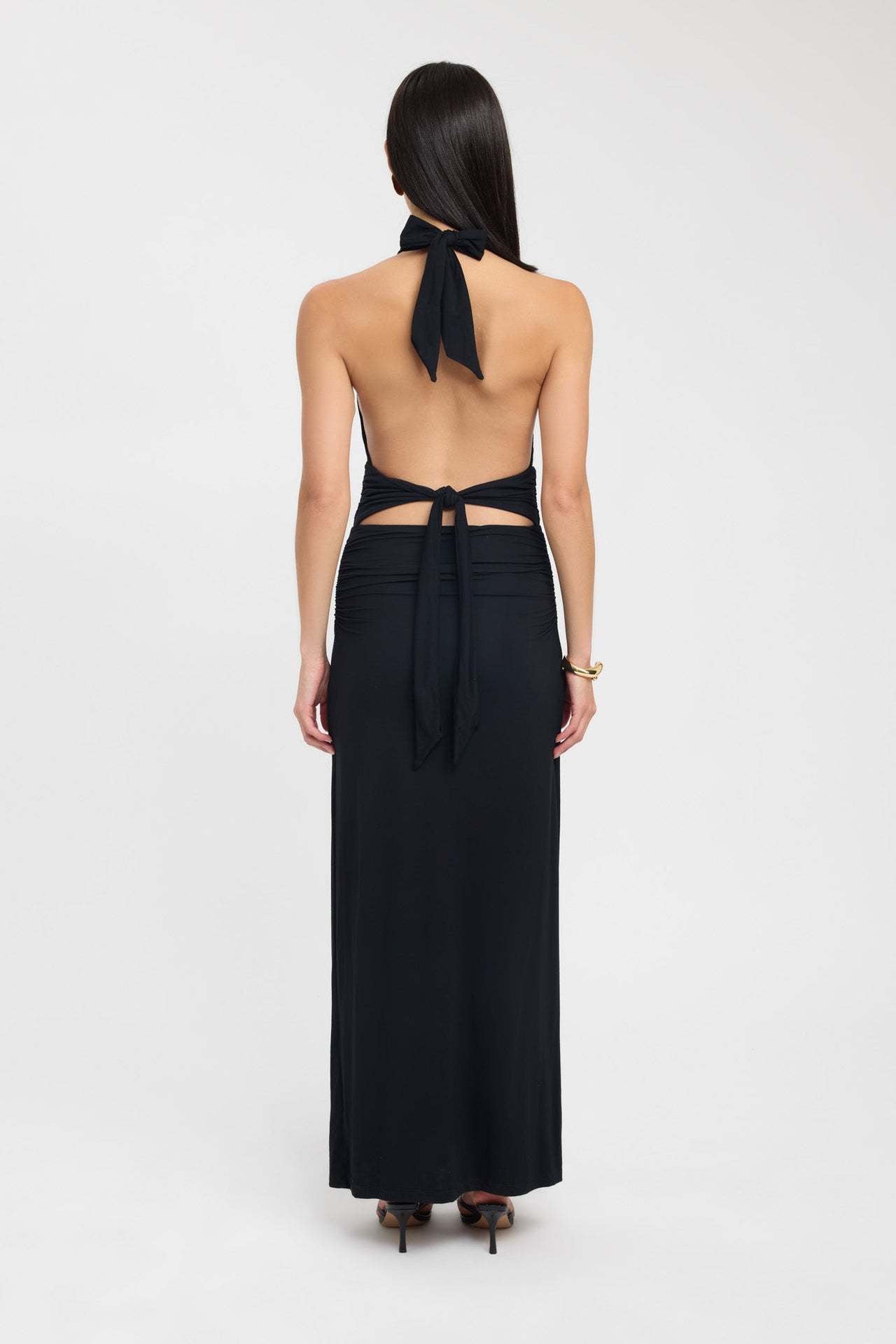 Rear view of a black ruched maxi dress, showcasing the halter tie closure and the elegant open back.