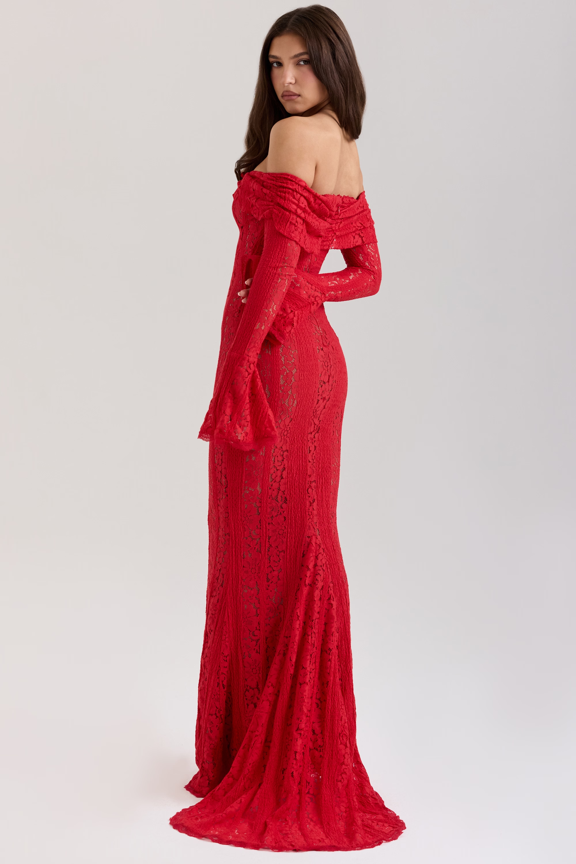 Back view of a woman wearing a red lace off-shoulder maxi dress with a small train for evening wear