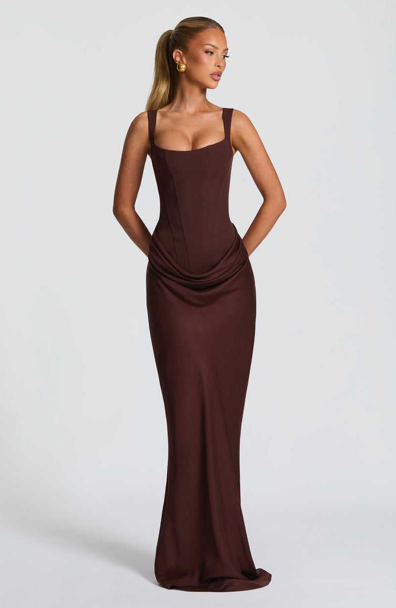 Full-length view of a chocolate brown Celeste Corset Maxi Dress with a sweetheart neckline and draped skirt detail.