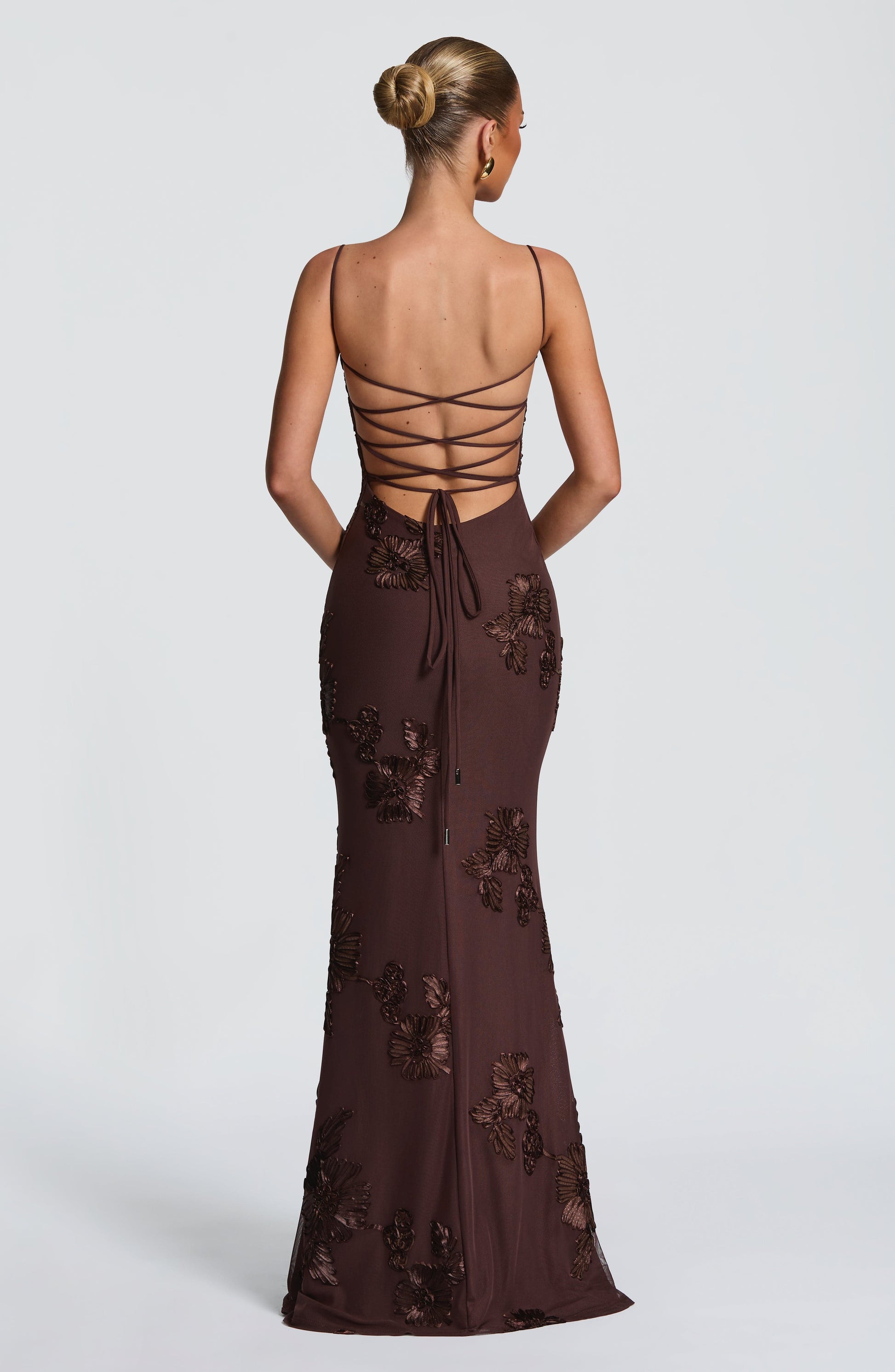 Back view of a brown floral maxi dress with delicate spaghetti straps and lace-up detailing, suitable for ladies evening gowns.
